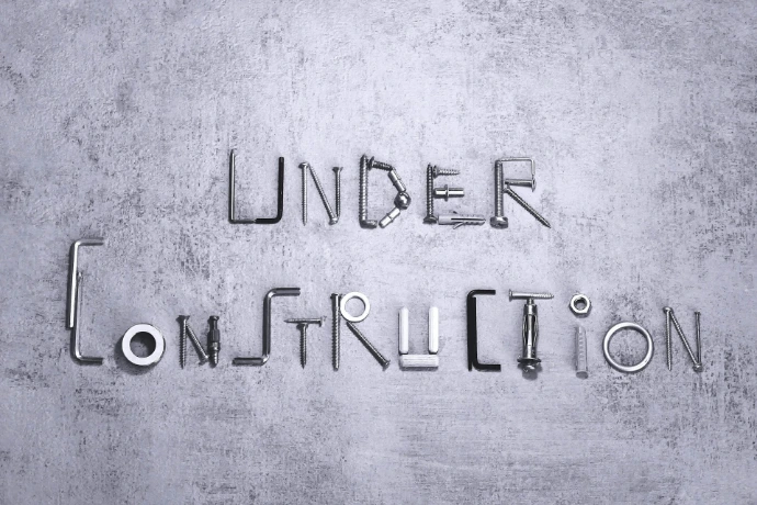 Under construction spelled with metal hardware on a gray background.
